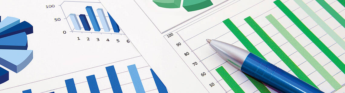 Kugelschreiber auf zwei Blättern mit Kreis- und Balkendiagrammen
