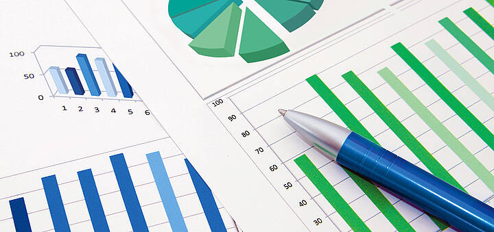 Kugelschreiber auf zwei Blättern mit Kreis- und Balkendiagrammen