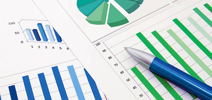 Kugelschreiber auf zwei Blättern mit Kreis- und Balkendiagrammen