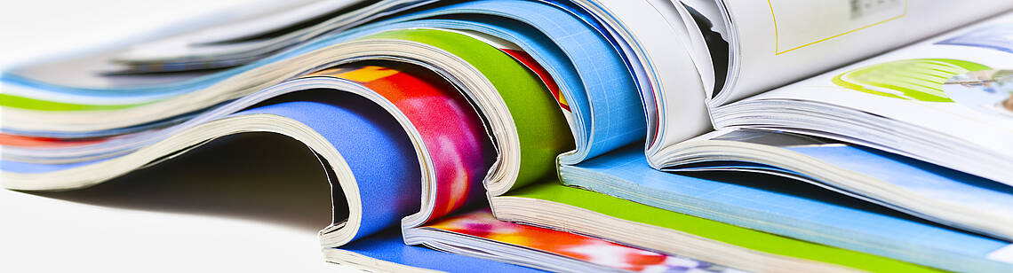 Mehrere Broschüren liegen aufgeschlagen aufeinander