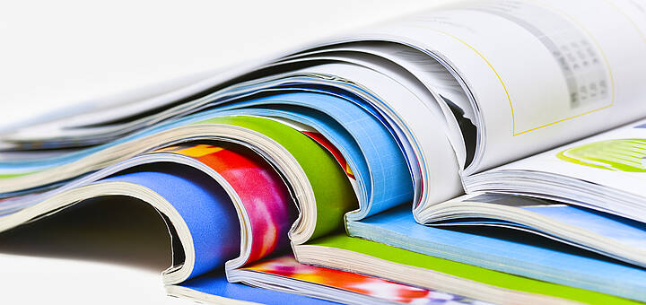Mehrere Broschüren liegen aufgeschlagen aufeinander