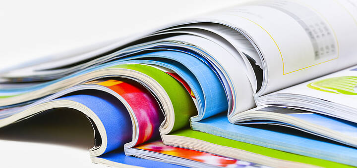 Mehrere Broschüren liegen aufgeschlagen aufeinander