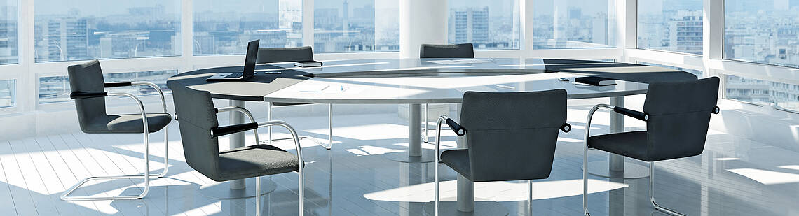 Konferenztisch mit Stühlen in einem modernen Büro mit großen Fensterflächen und Stadtsilhouette im Hintergrund